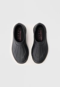 Black waterproof slip-on shoes with textured ribbed design, rounded toe, and cushioned insole. Insoles feature logo in contrasting color.