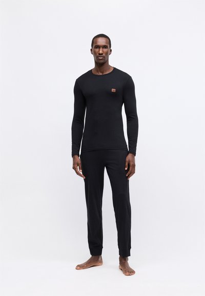 Crni longsleeve top i odgovarajuće hlače od mekanog materijala. Top ima mali logo na prsima, a hlače imaju uske manžete.