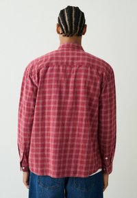 Rotes kariertes Langarmhemd aus strukturierter Stoffqualität, mit klappbarem Kragen, Knopfmanschetten und geradem Saum.