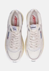 Sneaker atletiche bianche con tomaia in mesh testurizzato e pelle, lacci e suola in gomma gialla. Presentano il marchio nella linguetta e sul lato.