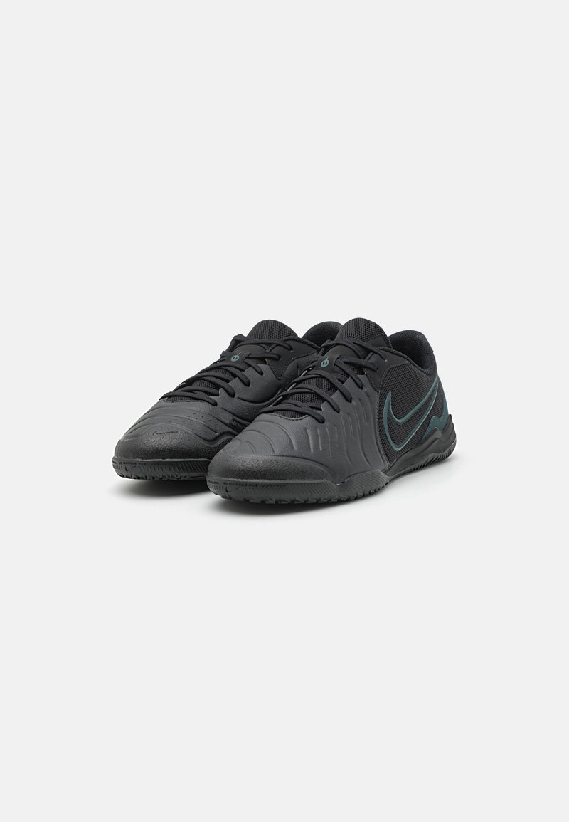 Baskets de sport noires avec une tige synthétique texturée, un design à lacets et une semelle en caoutchouc ; comprend des accents en teal sur le talon et le logo.