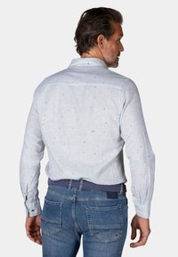 Lichtblauw, overhemd met lange mouwen met een gestreept patroon en multikleurige stippen. Voorzien van een standaard kraag en knoopmanchetten, gedragen met blauwe jeans.