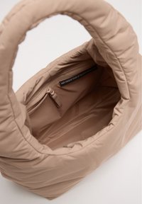 Borsa a tracolla beige trapuntata con un ampio interno, dotata di una tasca con zipper e manici rinforzati per una facile portabilità. Realizzata in materiali riciclati.