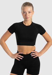 Zwart cropped sporttop met korte mouwen, gemaakt van rekbare stof. Heeft een geribbelde onderste zoom en een eenvoudig logo-label nabij de zoom.