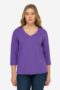 Lila Langarm-V-Ausschnitt-Shirt aus weichem Stoff mit lässiger Passform, das einen dezenten Logoakzent am Saum und eine standardmäßige Ärmel-Länge aufweist.