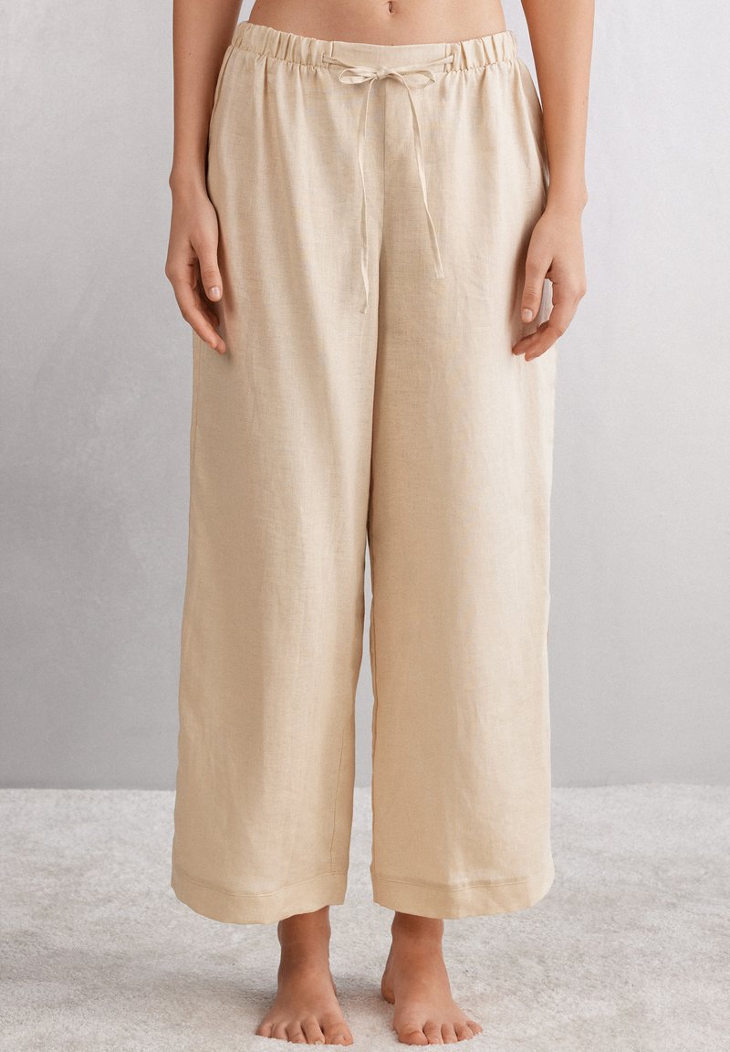 Beige Leinen-Hosen mit weitem Bein, elastischem Bund und Kordelzug, mit glatter Textur und gesäumten Säumen.
