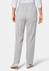 Lichtgrijze, geribbelde stofbroeken met een elastische tailleband. Rechthoekig ontwerp, minimale details, gedragen met beige schoenen.