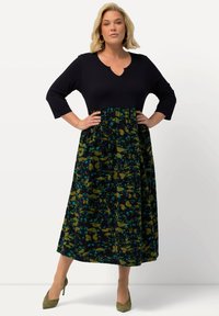 Robe longue avec un haut bleu marine à col en V et manches trois-quarts. La jupe présente un motif floral vert et bleu sur un fond sombre.