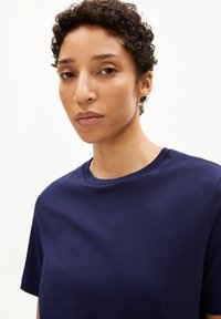 Marineblaue kurzärmelige T-Shirt mit rundem Halsausschnitt, aus weichem Stoff gefertigt, mit glatter Textur und minimalistischem Design.