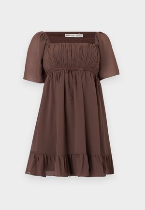 Καφέ κοντομάνικο φόρεμα με τετράγωνο ντεκολτέ, σούρα στο μπούστο, κορδέλα στη μέση και βολάν στο τελείωμα, κατασκευασμένο από ελαφρύ ύφασμα.