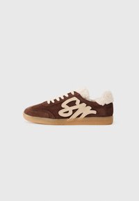 Brown suede sneaker with cream-colored faux fur lining and a prominent beige logo. Features white laces and a textured gum sole.