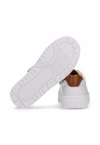Witte sneakers met een gladde leren buitenkant, bruine leren hielaccent en een getextureerde rubberen zool met zigzagpatronen en logo.