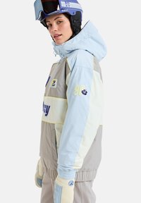 Skijack in lichtblauw, grijs en crème met een ritssluiting, elastische manchetten en geborduurde patches. Inclusief een capuchon en handschoenen.