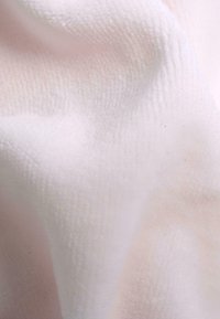 Blødt, tekstureret stof i lyserød med en subtil ribbet mønster, der udviser et glat og hyggeligt udseende.