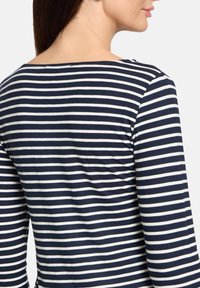 Gestreiftes Longsleeve-Oberteil in Marineblau und Weiß mit weitem Ausschnitt. Der Stoff wirkt weich mit einer glatten Textur und einem lässigen Schnitt.