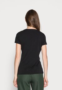 Camiseta negra de manga corta con cuello redondo y suave tela de algodón. Ajuste entallado con un dobladillo ligeramente curvado en la parte posterior.