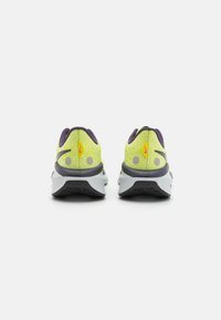 Nike jooksutossud, millel on erksalt kollane võrgust pealmine osa, lilla aktsent ja hall vaheosa. Omab pehmendatud kontsa ja tekstuuritud talla.