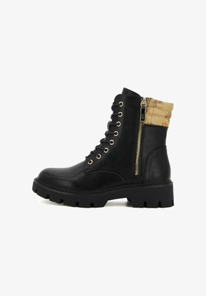 Stivaletto in pelle nera con un polsino in tessuto tan a trama. Presenta occhielli dorati, lacci anteriori e zip laterale. Suola spessa e robusta.