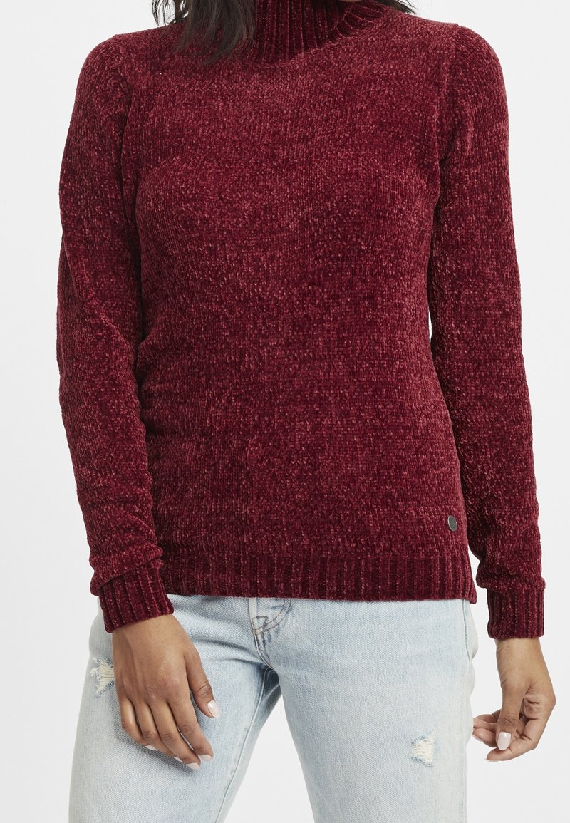 Bordeaux gebreide coltrui met geribde manchetten en zoom, met een gestructureerde afwerking en een klein logoaccent nabij de taille.