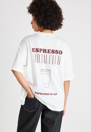 Tricou alb supradimensionat cu text cărămiziu și un grafic cu o cană de cafea pe spate, cu mâneci scurte și o croială lejeră.