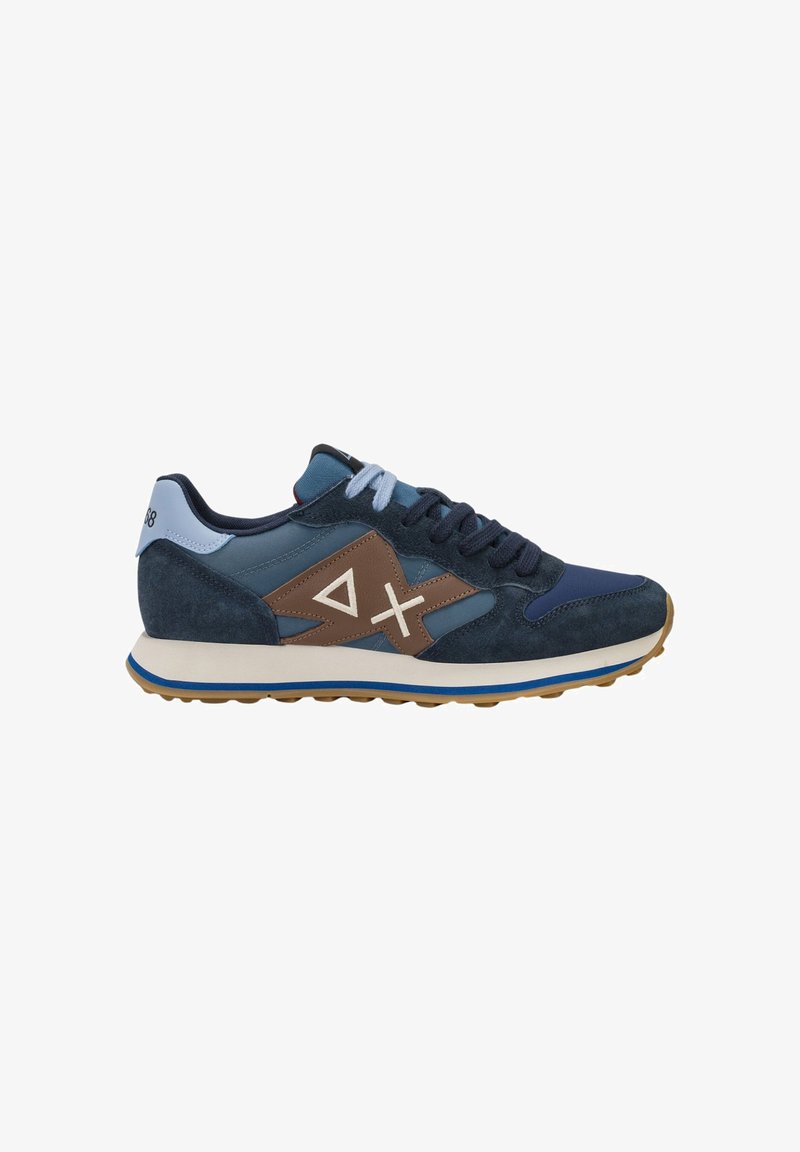 Baskets bleues et marron avec des lacets bleu clair, une semelle blanche et une semelle extérieure marron, présentant des formes géométriques sur le panneau latéral.