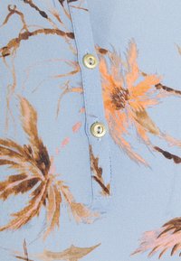 Světlé modré tkaniny s květinovými vzory v hnědé a oranžové barvě; obsahuje légu se stříbrným knoflíkem a jemnými detaily šití.