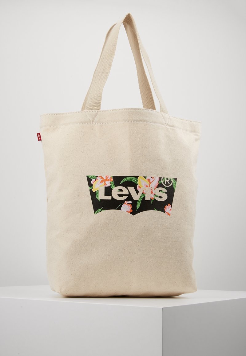 Canvas shoppingväska i naturlig färg med en svart Levis-logotyp prydd med färgglada blommor. Slitstarka dubbla handtag för enkel bärande.