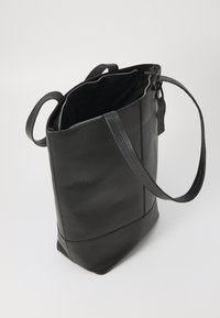 Borsa tote nera in pelle con una superficie testurizzata, chiusura con zip e due manici. L'interno è foderato in tessuto nero.