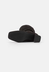 Schwarzer, samtener Stiefel mit Absatz und gerafftem Design. Quadratzehen und eine solide, schwarze, strukturierte Sohle. Mittelhoher Absatz.