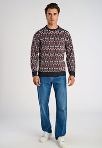 Stickad tröja med ett röd och marinblått mönster som visar vita renar. Ribbad halsringning och cuffs. Kombinationen med blå denimjeans och vita sneakers.