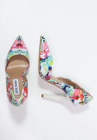 Chaussures à talons hauts florales avec un embout pointu, présentant un talon stiletto blanc, un motif floral multicolore éclatant et un design à dos ouvert.