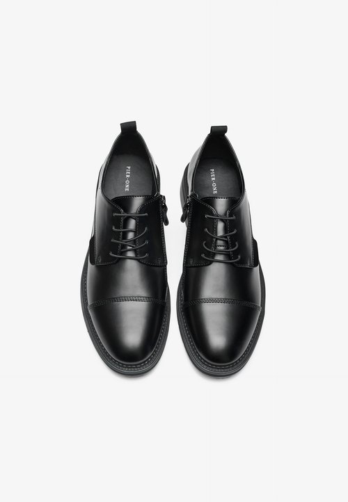 Chaussures en cuir noir avec une texture lisse, dotées d'un design à lacets, d'un embout arrondi et de subtils accents cousus sur le dessus.