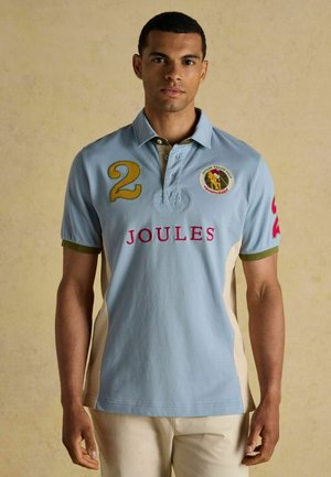 Hellblauses Poloshirt mit grünen und beigen Akzenten, bestickten Zahlen und einem Logo auf der Brust. Baumwollmaterial mit kurzen Ärmeln.