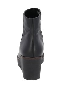 Bottines en cuir noir avec un talon bas, détail de fermeture éclair sur le côté et semelle en caoutchouc texturée. Lignes épurées et design élégant.