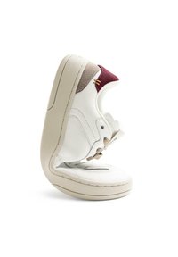 Sneaker in pelle bianca con accenti beige, forma arrotondata, suola in gomma texturizzata e dettagli color marrone scuro sul tallone e sulla linguetta.
