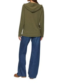 Olijfgroene hoodie met lange mouwen, zachte textuur en een rechte snit, gecombineerd met wijde blauwe denim broek.