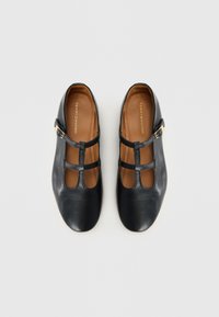 Black leather shoes with a smooth texture, rounded toe, and two horizontal straps. Features a gold-tone buckle accent and brown inner lining.