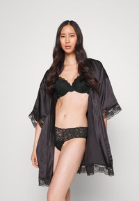 Black satin robe with lace trim, worn over a matching black lace bra and panty set. Smooth texture and delicate floral pattern on the lingerie.