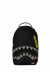 Zaino nero con un design a bocca di squalo grigio e nero, dotato di una tracolla con logo giallo e chiusura con doppizia. Finitura in tessuto liscio.