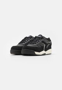 Black sneakers featuring a combination of suede and synthetic leather, with a textured surface, lace-up design, and white outsole accents.