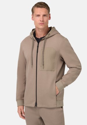 Beige zip-up hoodie lavet af blødt stof, med en kontrastfarvet lappelomme, hætte med snor og sidelommer med ribbede manchetter.
