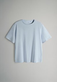 Šviesiai mėlynas medvilninis marškinėlis trumpomis rankovėmis, apvalia apykakle ir lygiu paviršiumi; forma laisva ir šiek tiek trumpinta krašte.