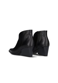 Botines de cuero negro con superficie texturizada, puntera redondeada y tacón cuadrado. Cuenta con una cremallera lateral para poner y quitar fácilmente.