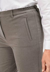 Grijze elastische broek met een gladde textuur, slanke pasvorm en zijzak met een subtiele glans, gestyled met een wit shirt.