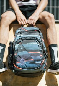 Mochila hecha de tela duradera, con un patr�ón multicolor de franjas azules, negras y rojas. Incluye un bolsillo lateral para botella de agua y cremalleras.