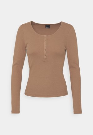 Haut marron à manches longues avec un col rond et une patte de boutonnage à cinq boutons à l'avant. Confectionné en tissu côtelé avec une silhouette ajustée.