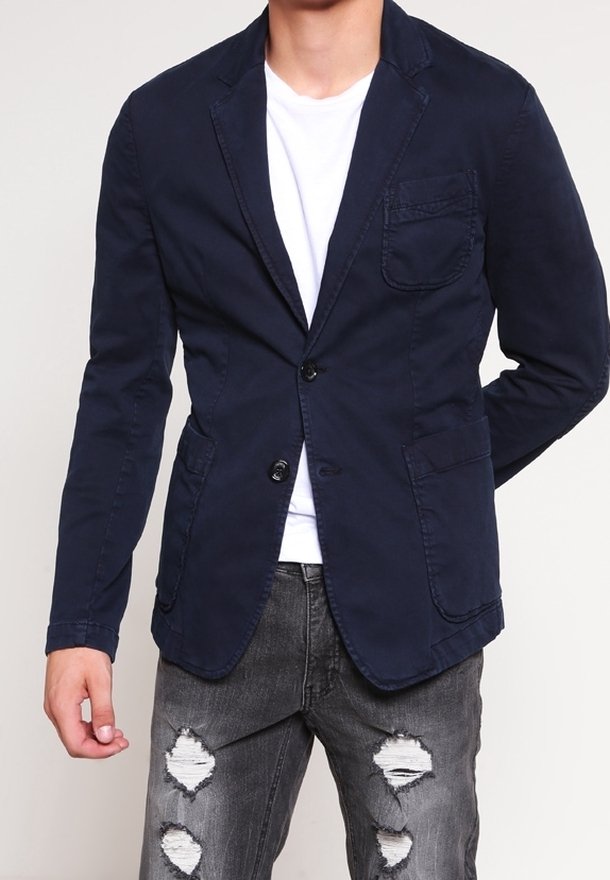 Blazer in cotone blu navy con design a petto singolo, revers a punta, due tasche frontali e una tasca sul petto, abbinato a jeans grigi effetto vissuto.