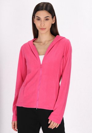 Fleece hoodie in felroze, met een ritssluiting, een capuchon, lange mouwen en een zachte textuur, gecombineerd met een witte top en zwarte broek.