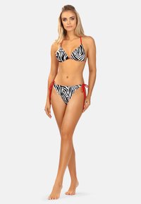 Czarny i biały bikini w paski zebry z czerwonymi ramiączkami; posiada trójkątny biustonosz i majtki z wiązaniem po bokach; gładki materiał i dopasowany krój.