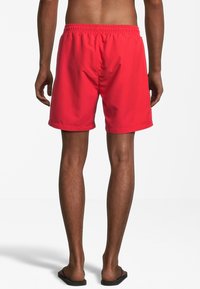 Röda badshorts med elastisk midja, tillverkade av lätt tyg, ovanför knät längd och med en slät yta. Inga synliga mönster.